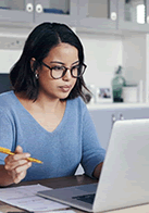 woman holding a pencil and looking at a laptop