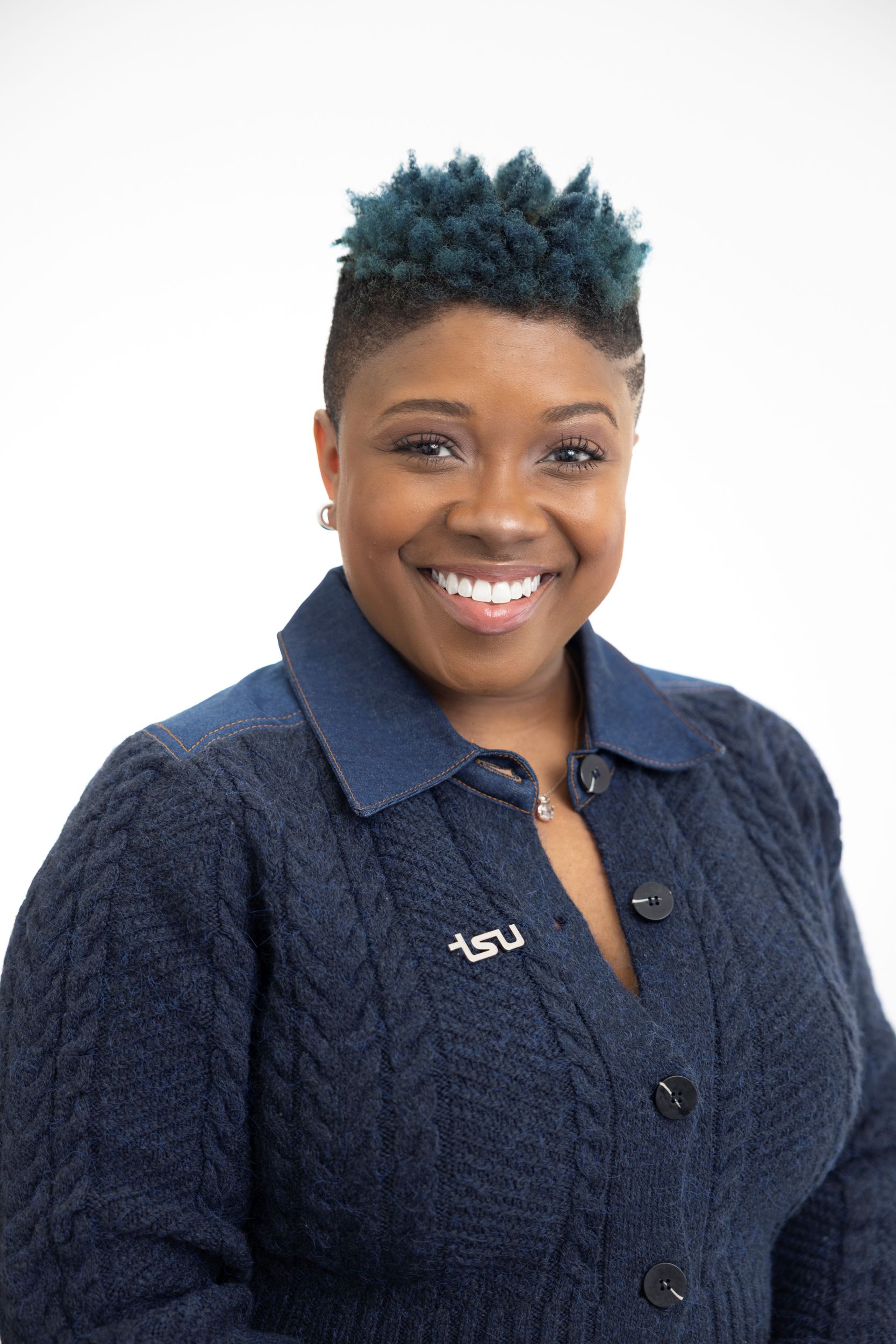 Woman smiling with blue sweater. TSU pin is affixed to the sweater